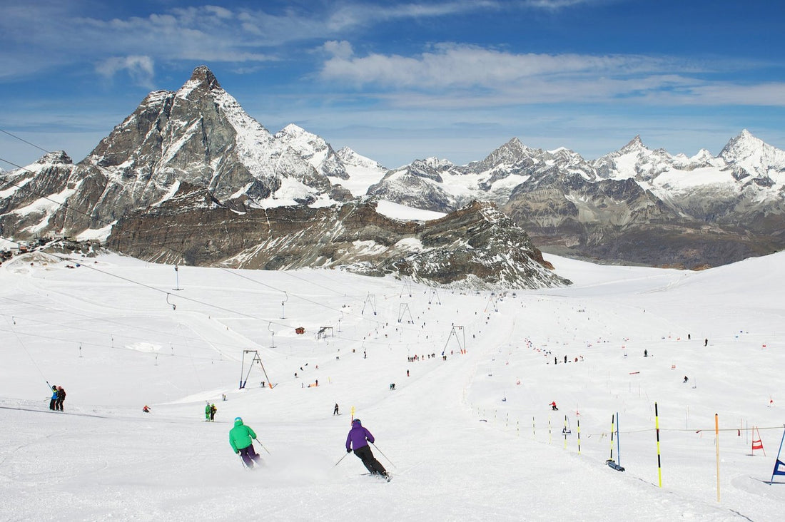 Two skiers make synchronised turns on the piste in Zermatt’s glacier on a sunny summer day.