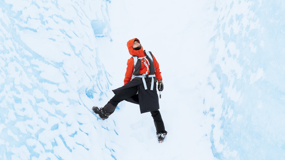 A woman in a red Houdini jacket looks around at her surroundings of blue ice.