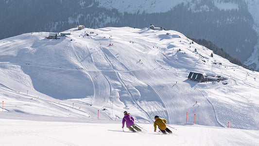 Two skiers lean into a left turns skiing the piste in Arosa