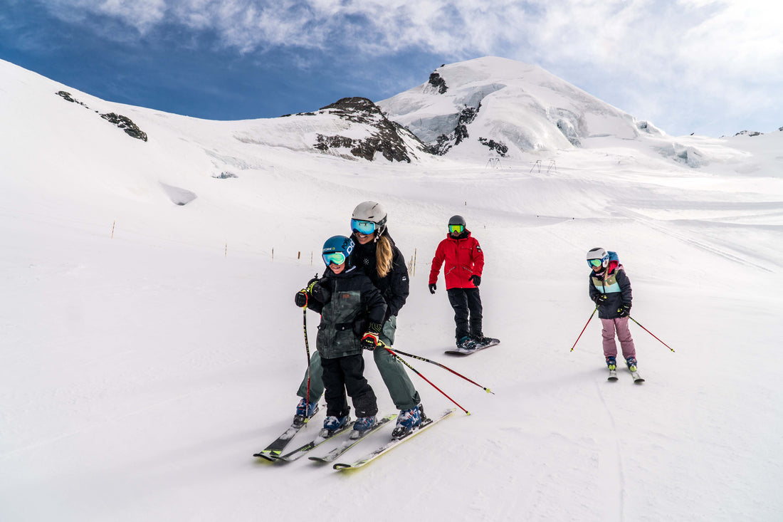 A family of 4 having fun in the ski resort of Saas-Fee, 3 of them are skiing and 1 is snowboarding