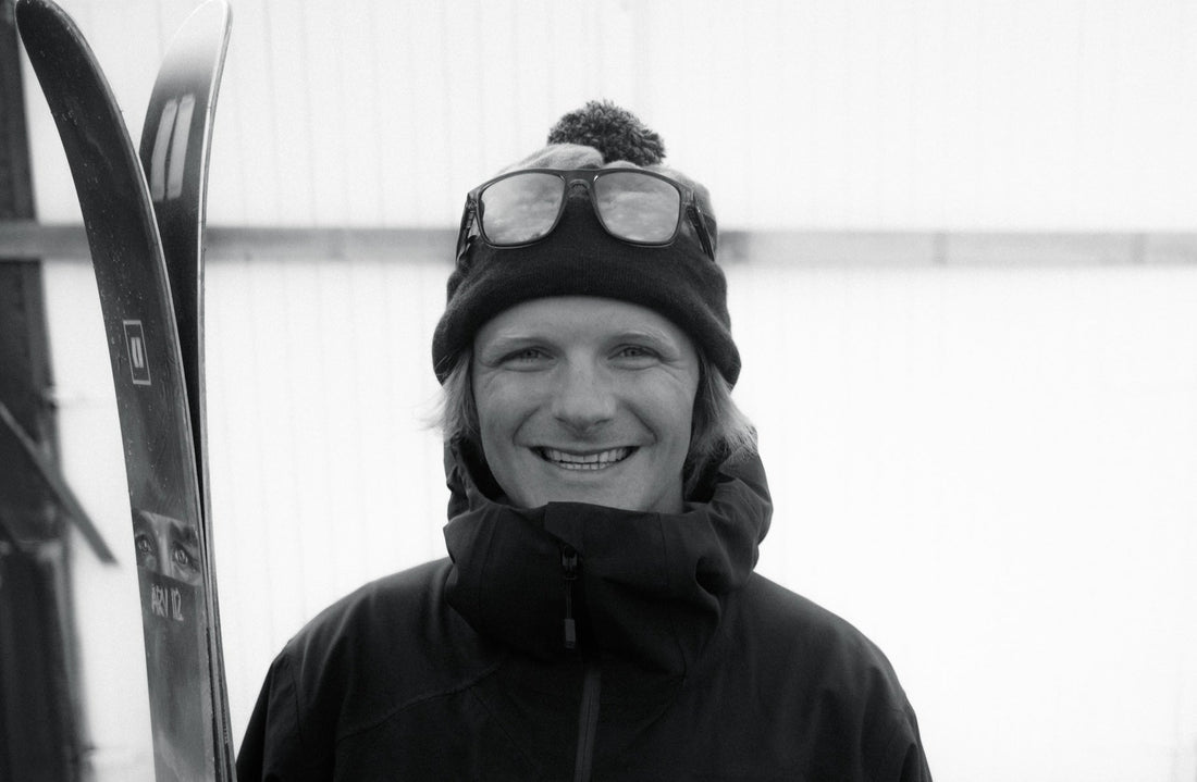 A portrait of German freeride skier, Konsti Ottner. He is smiling and has his skis next to him. 