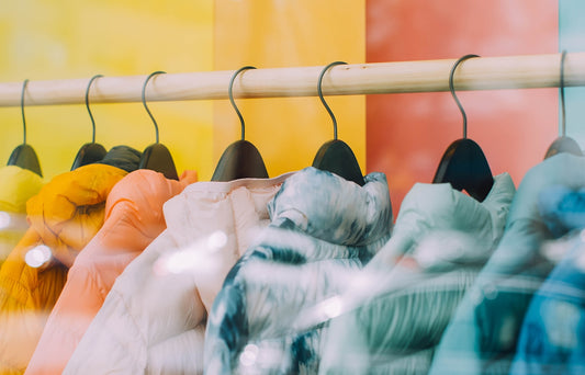 A colourful rack of insulated jackets arranged in the colours of the rainbow.