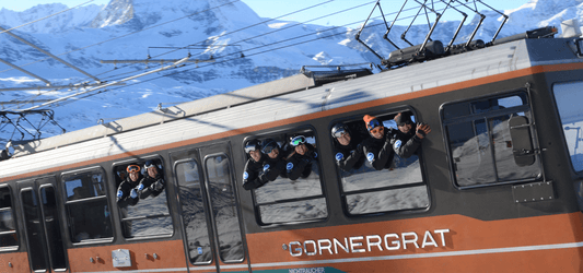 Eight European Snowsport ski instructors hanging out the windows of the Gornergrat train